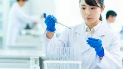 白衣を着てピペット操作をする様子。
