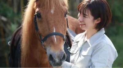 馬のそばに立つ女性。